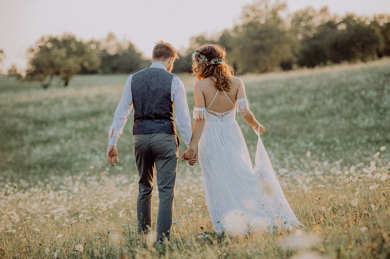 bride and groom walking in wild flower field