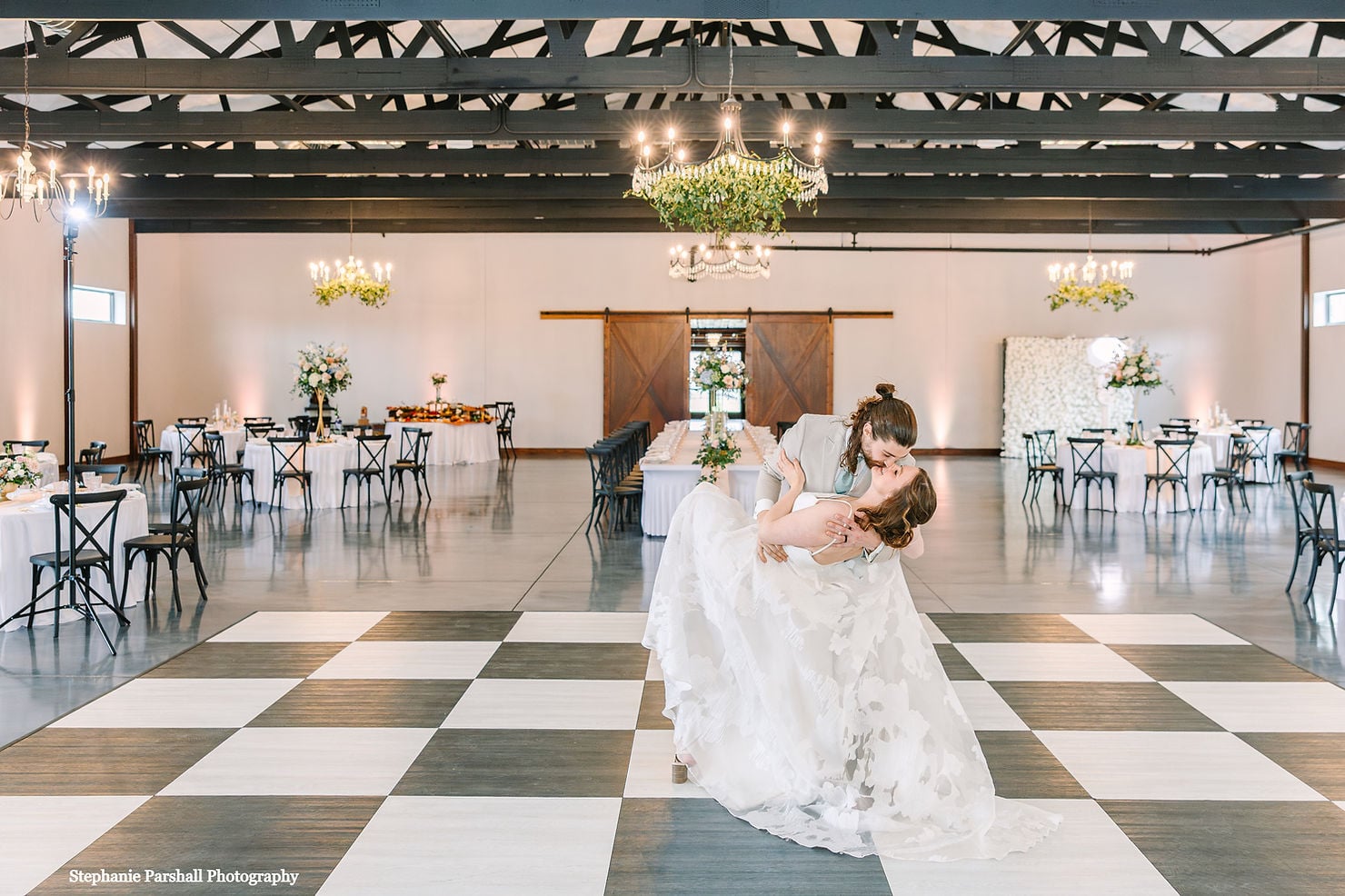 Couple dip and kiss on the checkered dance floor. 